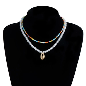 Close-up of bohemian layered necklace with colorful beads and gold shell pendant