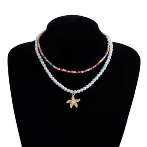 Close-up of double-layer beaded necklace featuring a golden starfish shell pendant