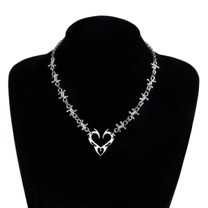 Detailed close-up of Y2K punk style silver thorn heart pendant necklace on black model