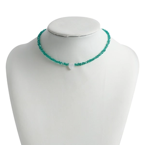 Close-up of green crystal beaded necklace with a white heart pendant on jewelry bust