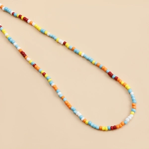 Close-up of bohemian colorful beads necklace with bright resin beads on beige background