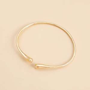 Detailed close-up of a minimalist gold teardrop choker necklace with polished finish