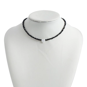 Detail of beaded necklace with black chips and white heart on a model bust