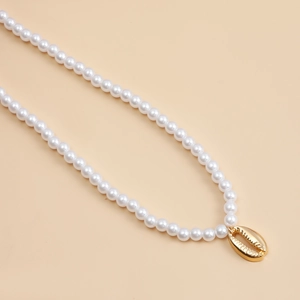 Detailed close-up of a white pearl necklace with a polished gold shell pendant