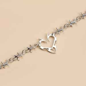 Detailed view of silver heart pendant with punk style barbed wire chain texture