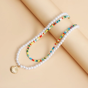 Detail of bohemian layered necklace with colorful beads, pearls and golden shell pendant