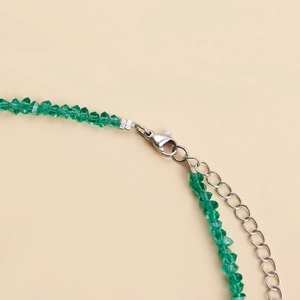 Macro view of green faceted crystal bead necklace with silver lobster clasp and extension chain