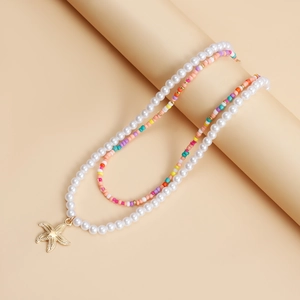 Detail of bohemian layered necklace featuring faux pearls and a gold starfish charm