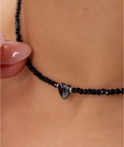 Macro-opname van een zwarte kralen choker met een gepolijste metalen hartvormige hanger