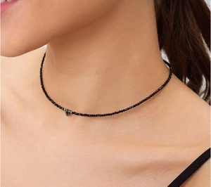 Detailopname van zwarte kralen choker ketting met een verfijnde metalen hartvormige hanger