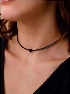 Detailopname van zwarte kralenchoker met glanzende hartvormige hanger gedragen om nek