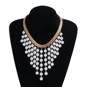 Close-up of golden multi-layer tassel necklace with white pearls on a black display stand