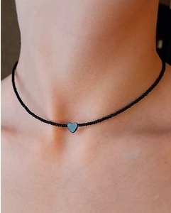 Detailopname van een zwarte kralen choker met een donkergrijs hartvormig hangertje bij een model