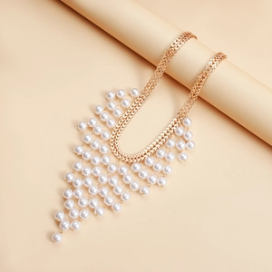 Macro detail of multi-layer gold chain necklace with cascading white pearl fringe