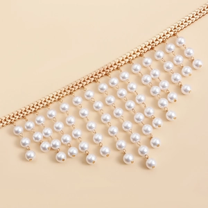Detail of gold metal V-chain with multi-layered white pearl fringe tassels on beige background