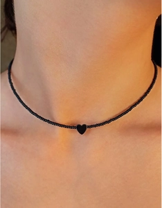 Close-up van de minimalistische zwarte kralenketting met een gepolijste hartvormige hanger