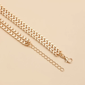 Detailed view of the golden V-shaped geometric links and lobster clasp on this necklace
