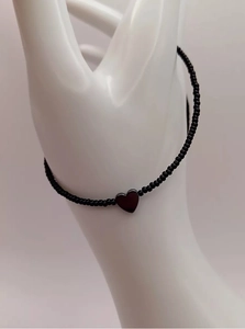 Detailopname van een zwarte kralenketting met hartvormige hanger op een handmodel gepresenteerd