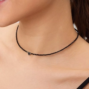 Minimalistische zwarte kralen choker met hartvormige hanger gedragen door model