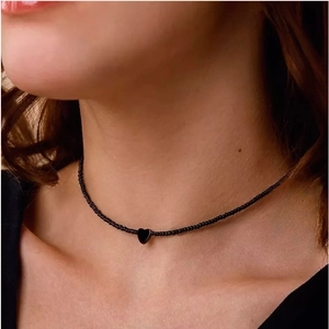 Minimalistische zwarte kralen choker met glanzende hart hanger gedragen door model