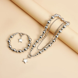 Detail shot of silver star pendant necklace and bracelet set on a soft beige stand