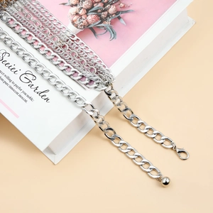 Detail of silver layered body chains with lobster clasp on a white decorative surface
