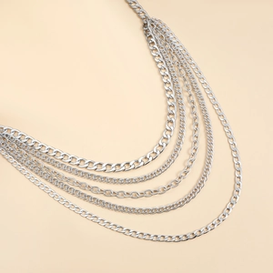 Detail of layered silver metal body chain with mixed Cuban and fine link textures