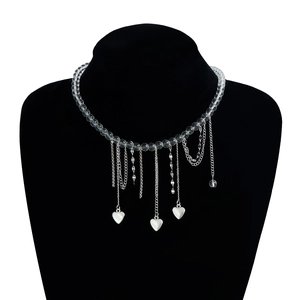 Detail view of transparent beaded necklace with silver heart charms and long tassels