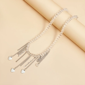 Detail of transparent beaded necklace with silver heart charms and tiered fringe chains