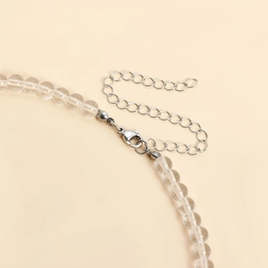 Detail of transparent beaded necklace with silver lobster clasp and adjustable metal extension chain