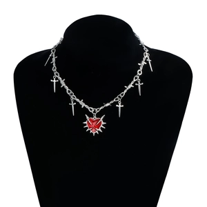 Detalle macro del collar punk gótico con colgante de corazón rojo y cadena con espinas