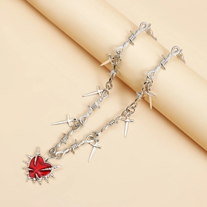 Detalle de collar punk con espadas plateadas y colgante de corazón rojo con espinas