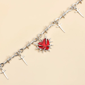 Detalle de gargantilla punk con cadenas de espinas, corazón rojo y cruces de plata