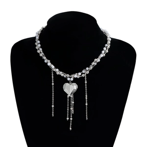 Dettaglio della collana con ciondolo a cuore argento, perline e lunghe nappe in metallo