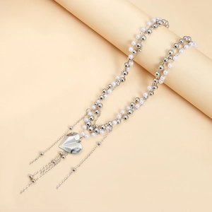 Dettaglio di collana a strati con perline d'argento, ciondolo a cuore e nappe di perle