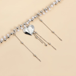 Dettaglio della collana con pendente a cuore argento con lunghe nappe e perle bianche
