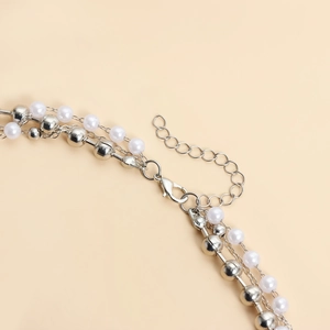 Dettaglio della collana di perle a strati con perline di metallo e catena di estensione