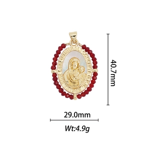 Detail of 18k gold plated religious medal with white shell inlay and red beads