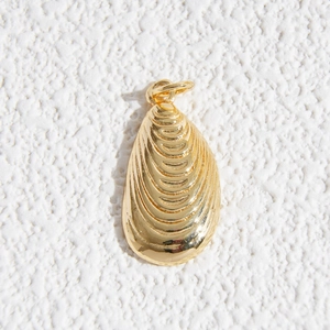 Dettaglio di un ciondolo a forma di cozza dorata con texture realistica e un gancio