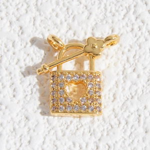 Dettaglio macro di un ciondolo a lucchetto a cuore dorato con strass e chiusura a T