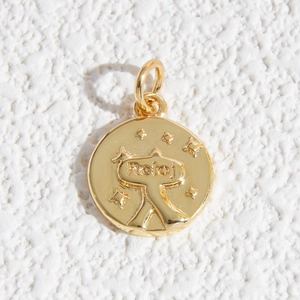 Vista macro del ciondolo d'oro con testo Reloj e stelle su sfondo di pietra
