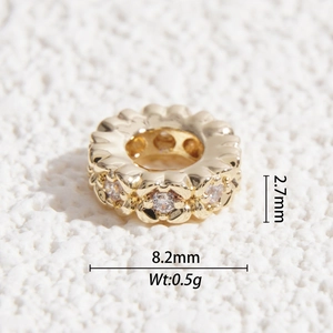 Macro detail of gold spacer bead with faceted clear zircons and wavy petal edges