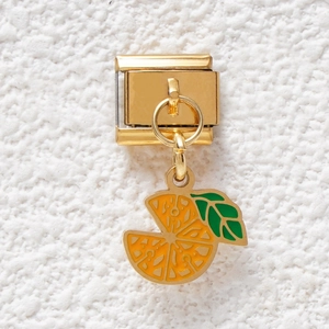 Macro shot of gold Italian charm link featuring a detailed orange slice with green leaf