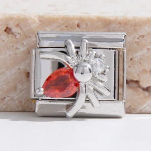 Détail macro du maillon Italian Charm avec araignée en acier et zircon orange brillant