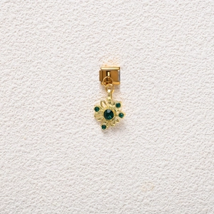 Detailed view of golden Italian charm link with green gemstone floral pendant