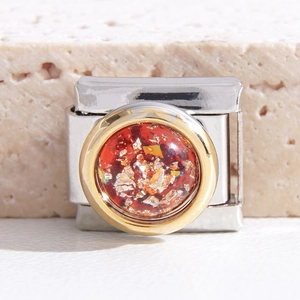 Makro-Detail des italienischen Modul-Charms mit rotem Stein und Goldblatt aus Edelstahl