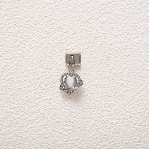 Macro shot of a silver Italian charm featuring a heart opal and sparkling rhinestones