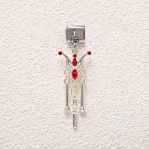 Close-up of Italian charm with red gemstones and metallic tassels for DIY bracelets