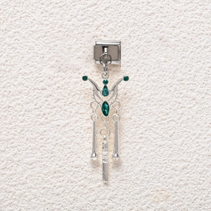 Macro detail of silver DIY modular charm with deep green gemstones and metal wings