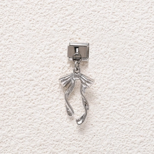 Detailed view of a silver steel bow pendant for DIY modular link bracelets with tassels